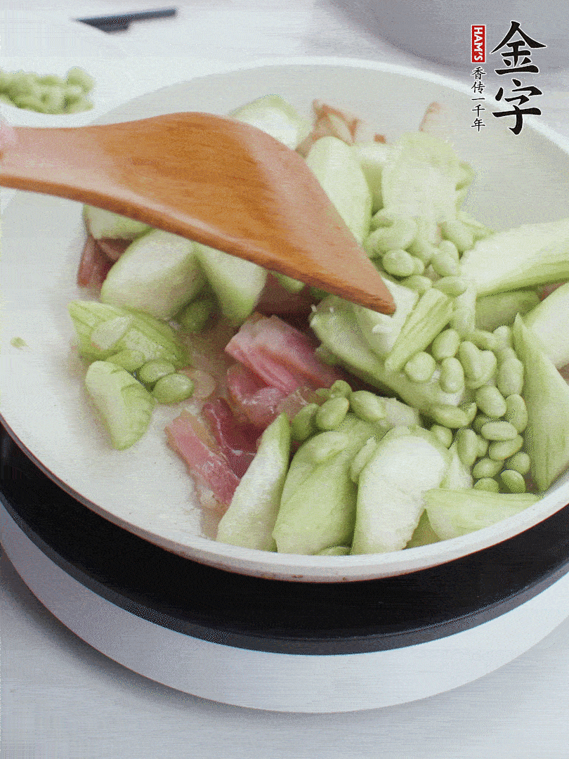 依次下絲瓜、青豆翻炒，炒至絲瓜打蔫縮小。