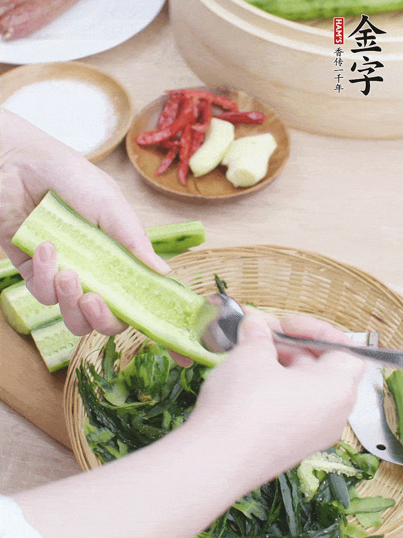 黃瓜削皮，對半切開，勺子挖去內(nèi)瓤，斜刀切片。青蒜斜刀切段。