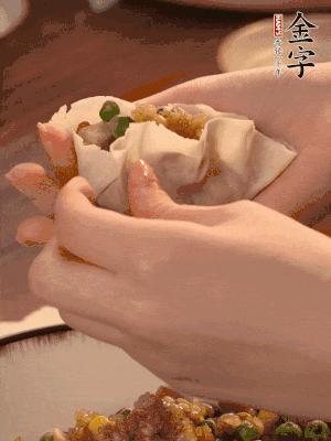 取一大勺餡料放進(jìn)餃子皮里，用大拇指按住頂部餡料，再用虎口掐出形狀。