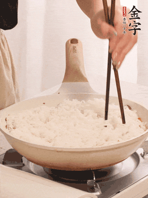 把瀝干水分的米飯均勻鋪在上面，筷子戳幾個(gè)洞，以便透氣，轉(zhuǎn)小火蓋上蓋子燜至水分收干，大概10分鐘。
